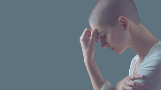 woman with cancer touching her forehead