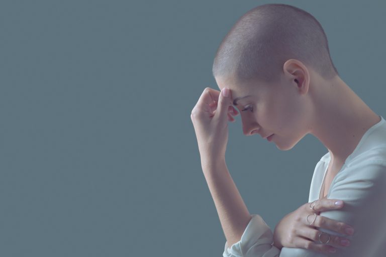 woman with cancer touching her forehead