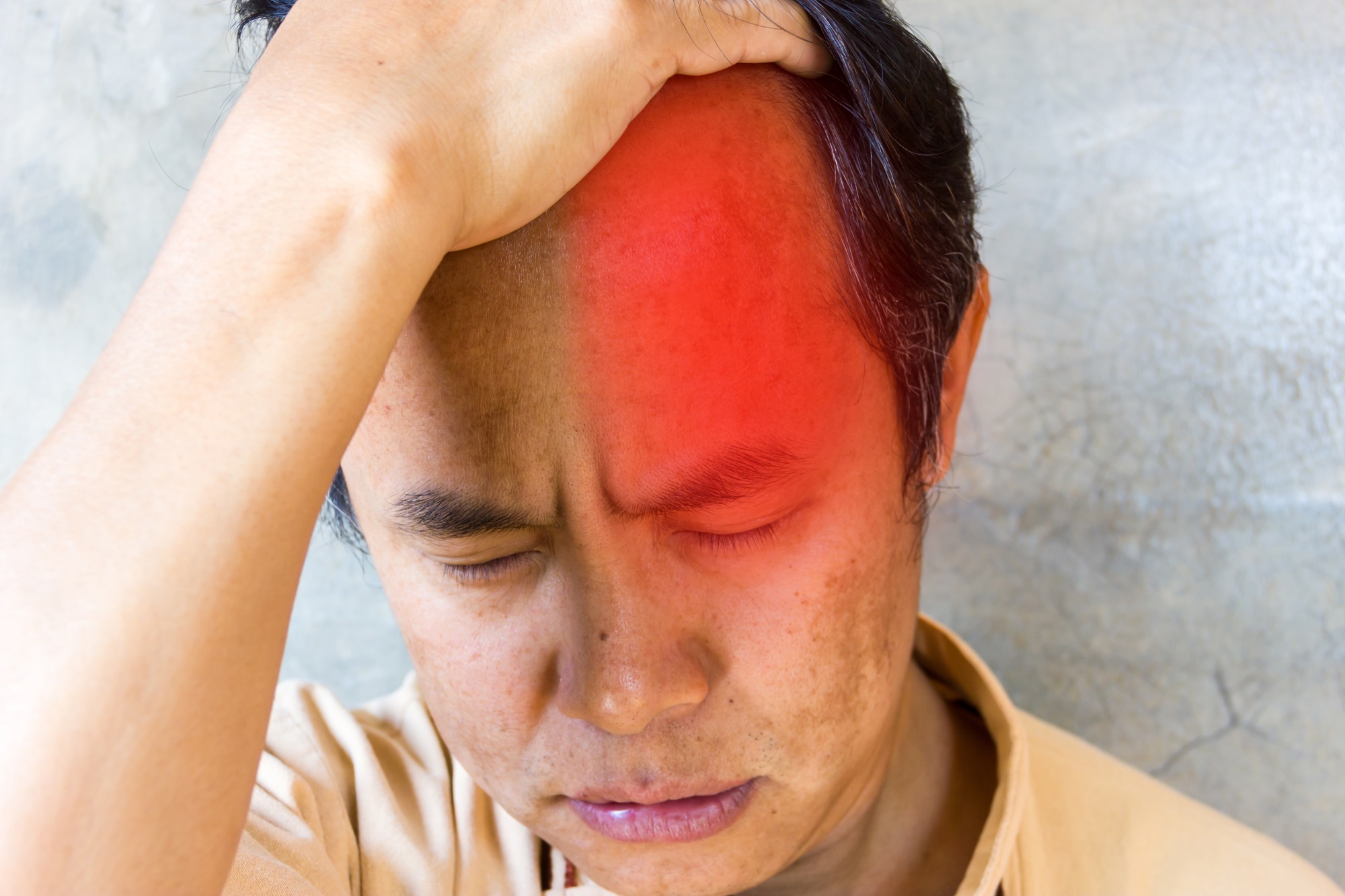 man holding his head with a red spot indicating a cluster headache