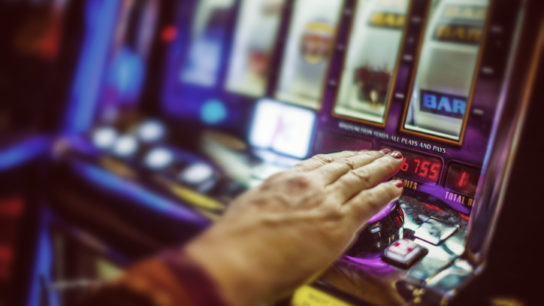 older adult's hand on slot machine
