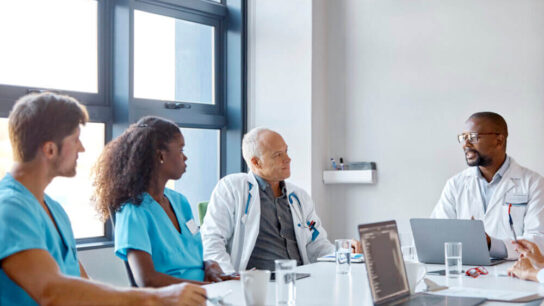 Healthcare-worker-talking-with-professionals-in-meeting.