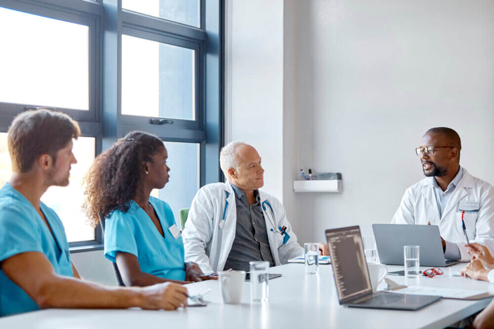 Healthcare-worker-talking-with-professionals-in-meeting.