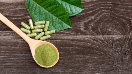 Flat-lay-top-view-of-fresh-green-kratom-leaf-with-kratom-powder-isolated-on-wooden-table-background.