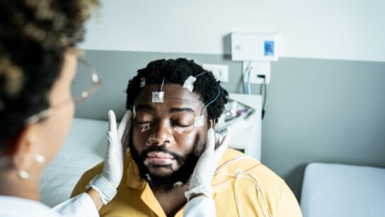 Doctor-placing-electrodes-on-patient's-head-for-a-polysomnography