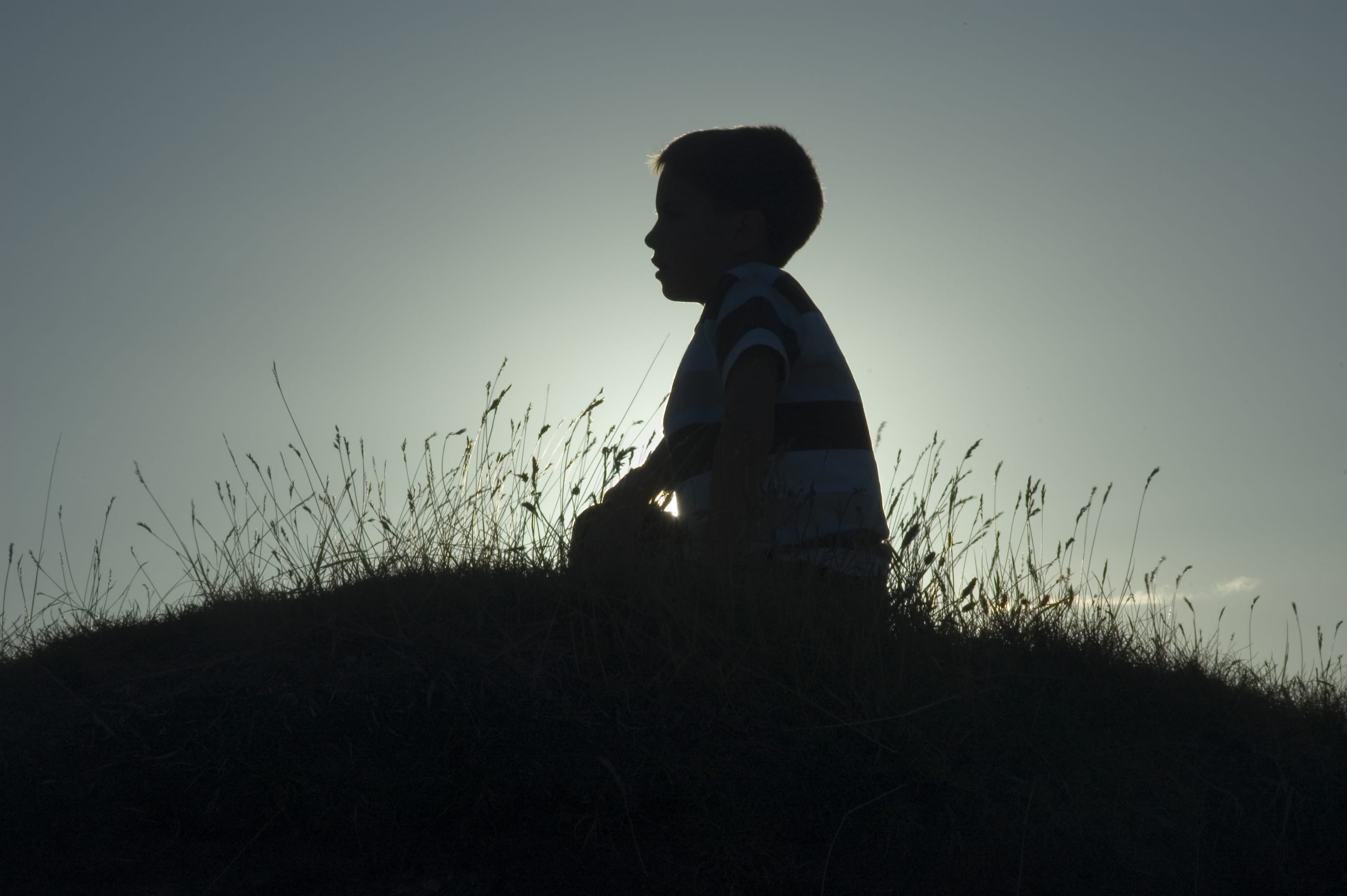 silhouette of boy on hill