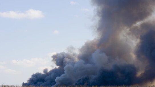 Helicopter-near-smoke-caused-by-brush-fire-behind-houses