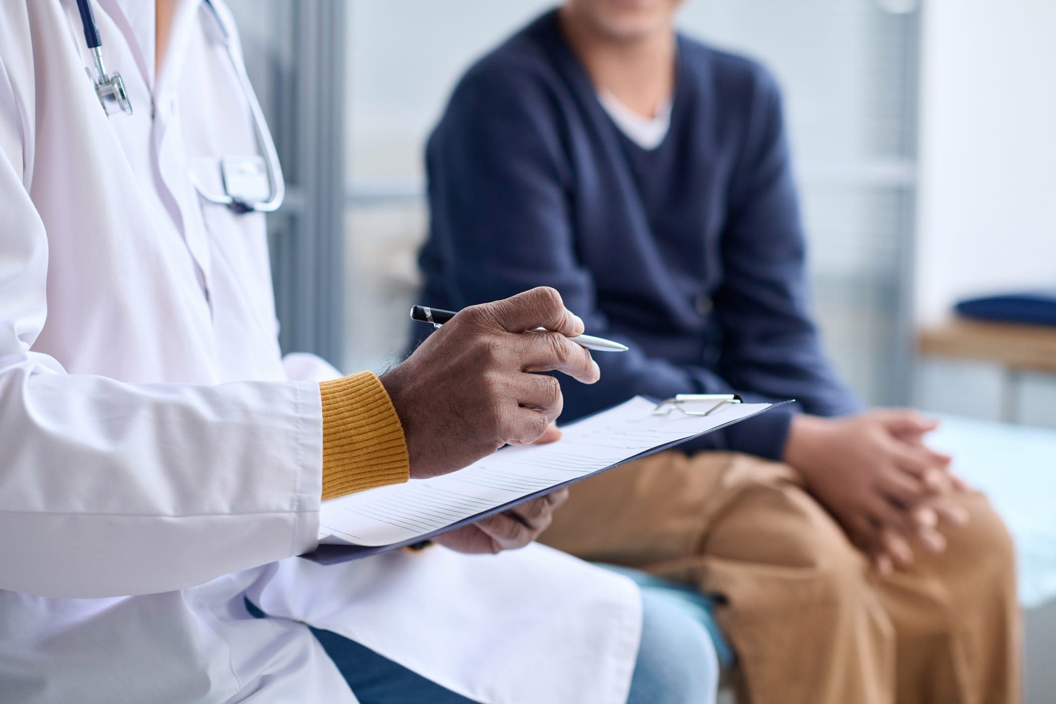Side-view-closeup-of-Middle-Eastern-doctor-holding-clipboard-while-consulting-child-in-clinic-copy-space