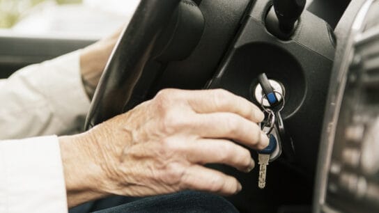 senior woman putting car key in ignition lock