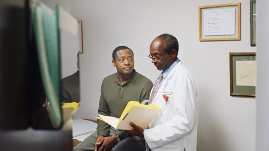 male doctor standing next to male patient