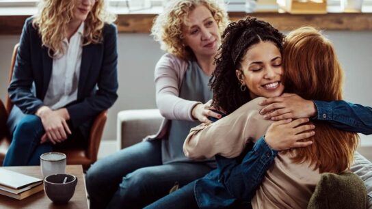female-patients-in-group-therapy-one-woman-hugging-another-woman