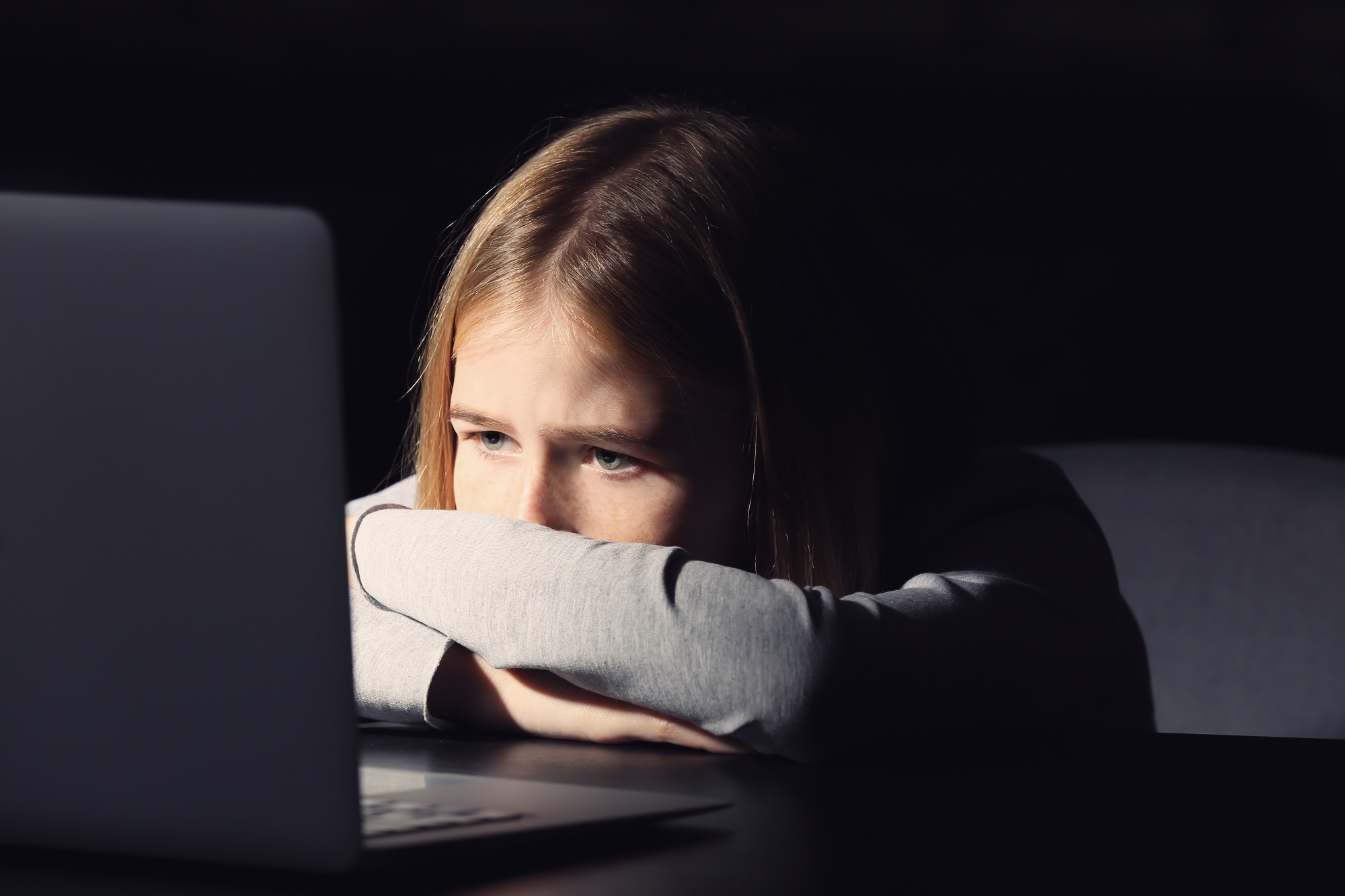 Depressed girl sitting in front of laptop.